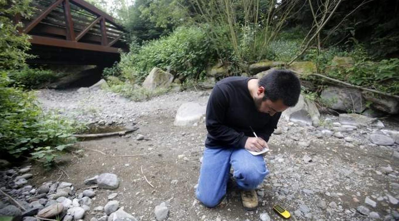 Student taking measurements in a dry creek bed